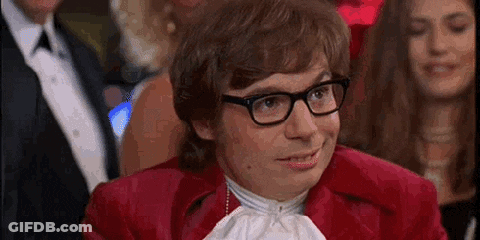 A Man In A Red Suit And Glasses Is Sitting In A Crowd . GIF