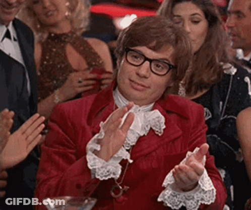 A Man In A Red Suit Is Clapping His Hands In A Crowd Of People . GIF