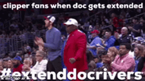 A Man In A Red Suit Is Dancing In A Crowd Of People At A Basketball Game . GIF