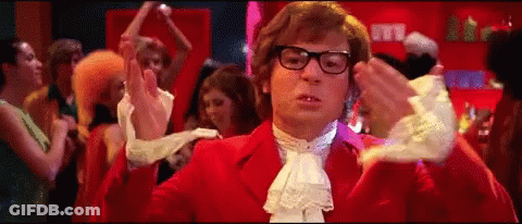 A Man In A Red Suit Is Dancing In Front Of A Crowd Of People . GIF