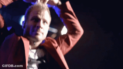A Man In A Red Suit Is Dancing On Stage GIF