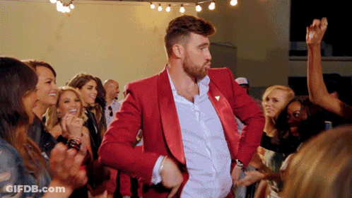 A Man In A Red Suit Is Dancing With A Crowd Of People GIF