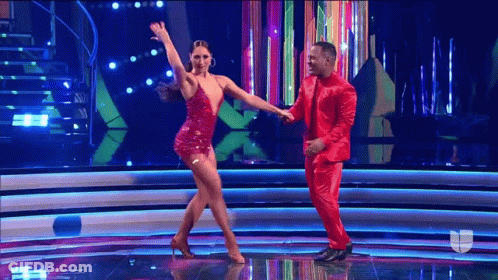 A Man In A Red Suit Is Dancing With A Woman In A Red Dress . GIF