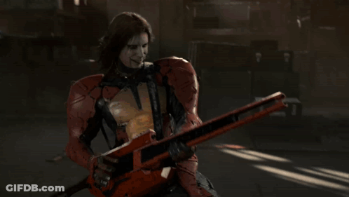 A Man In A Red Suit Is Holding A Guitar GIF