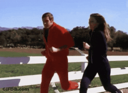 A Man In A Red Suit Is Running With A Woman In Black Pants GIF