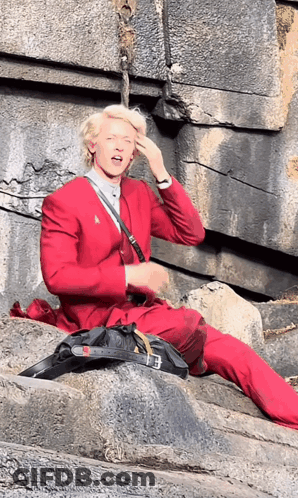 A Man In A Red Suit Is Sitting On The Ground GIF