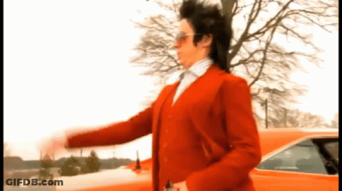 A Man In A Red Suit Is Standing In Front Of A Red Car GIF