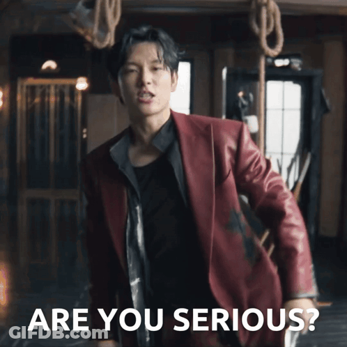A Man In A Red Suit Is Standing In Front Of Ropes And The Words Are You Serious GIF