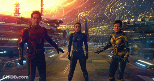 Man In Red Suit Next To Two Women In Blue Suits GIF
