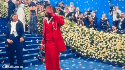 A Man In A Red Suit Is Standing On A Staircase In Front Of A Crowd Of People . GIF