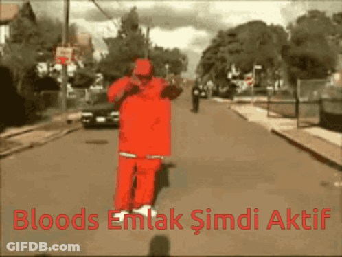 A Man In A Red Suit Is Walking Down A Street With The Words Bloods Emlak Şimdi Aktif Written Below Him GIF