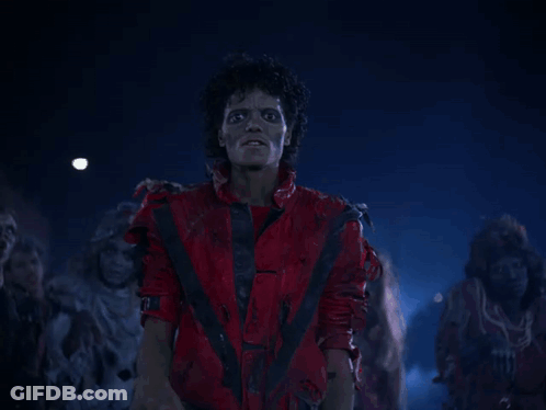 A Man In A Red Suit Stands In Front Of A Group Of Zombies GIF