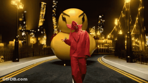 A Man In A Red Suit Stands In Front Of A Large Yellow Ball GIF