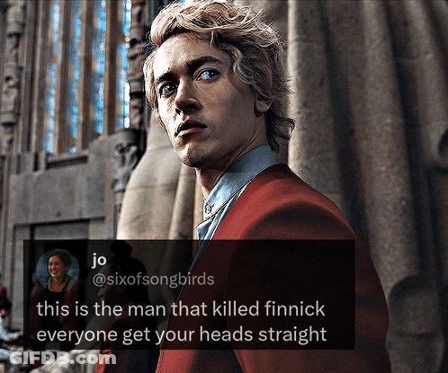 A Man In A Red Suit Stands In Front Of A Stained Glass Window GIF