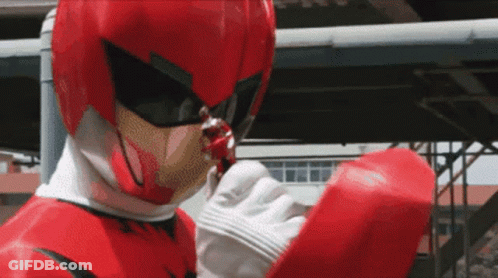 A Man In A Red Superhero Costume Is Holding Something In His Hand GIF