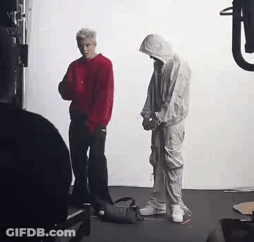 A Man In A Red Sweater And A Man In A White Suit Are Standing Next To Each Other In A Room . GIF
