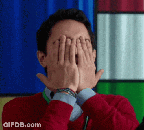 A Man In A Red Sweater Is Covering His Eyes With His Hands GIF