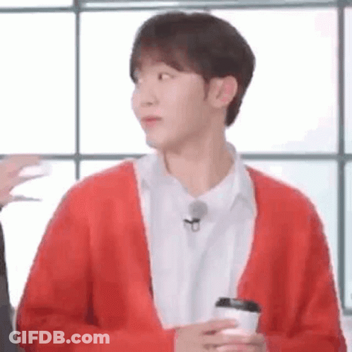 A Man In A Red Sweater Is Holding A Cup Of Coffee . GIF