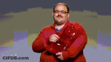 A Man In A Red Sweater Is Holding A Red Object In His Hands GIF