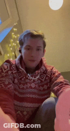 A Man In A Red Sweater Is Sitting On A Couch GIF