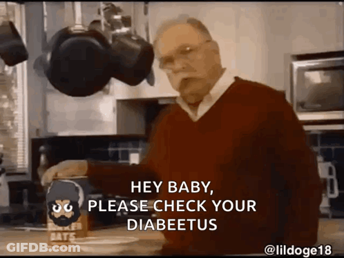 A Man In A Red Sweater Is Standing In A Kitchen With A Box Of Baker 'S Oats On The Counter GIF