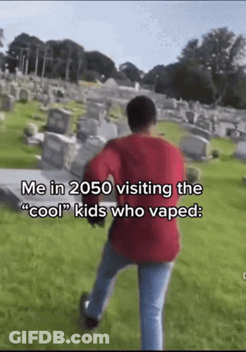 A Man In A Red Sweater Is Walking Through A Cemetery With The Caption " Me In 2050 Visiting The Cool Kids Who Vaped " GIF