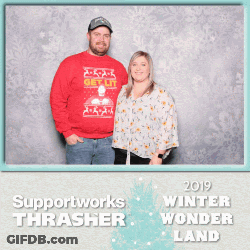 A Man In A Red Sweater Stands Next To A Woman In A White Floral Shirt GIF