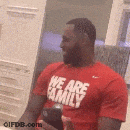 A Man In A Red T-Shirt That Says `` We Are Family '' Is Holding A Cell Phone . GIF