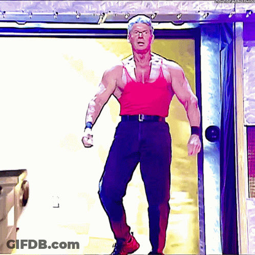 A Man In A Red Tank Top Is Standing In Front Of A Door GIF