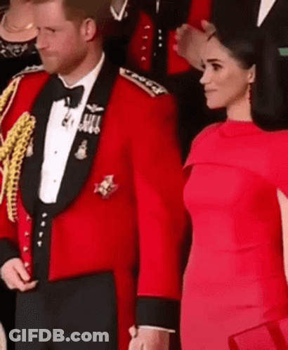A Man In A Red Tuxedo And A Woman In A Red Dress Are Standing Next To Each Other And Holding Hands . GIF