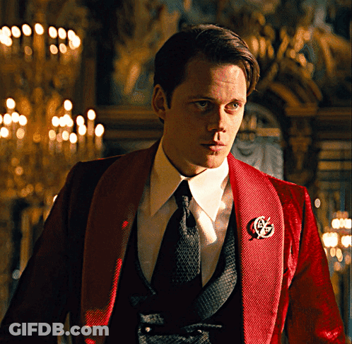 A Man In A Red Tuxedo Has A G On His Jacket GIF