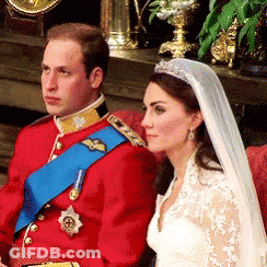 A Man In A Red Uniform Sits Next To A Woman In A White Dress And Veil GIF