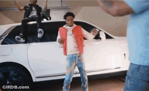 A Man In A Red Vest Is Dancing In Front Of A White Limousine GIF