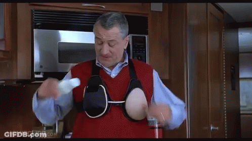 A Man In A Red Vest Is Holding A Bottle In His Hands In A Kitchen .. GIF