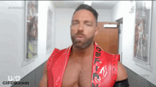 A Man In A Red Vest Is Standing In A Hallway GIF