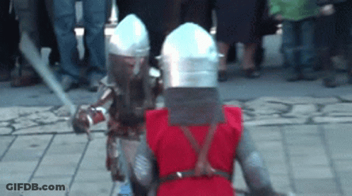 A Man In A Red Vest Is Standing Next To A Man In A Knight Costume GIF
