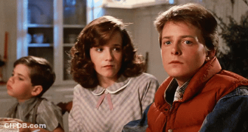 A Man In A Red Vest Sits At A Table With A Woman And A Boy GIF