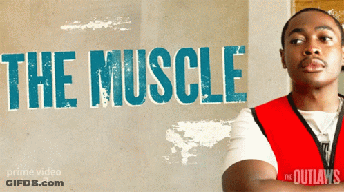 A Man In A Red Vest Stands In Front Of A Wall That Says The Muscle GIF