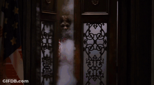 A Man In A Red White And Blue Outfit Is Standing In Front Of A Window GIF