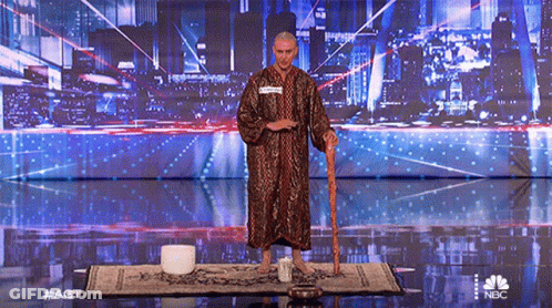 A Man In A Robe Is Standing On A Stage With A Cane And A Nbc Logo In The Background GIF