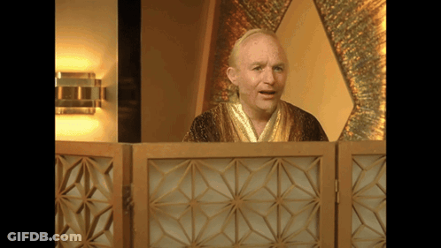 A Man In A Robe Stands Behind A Wooden Partition GIF