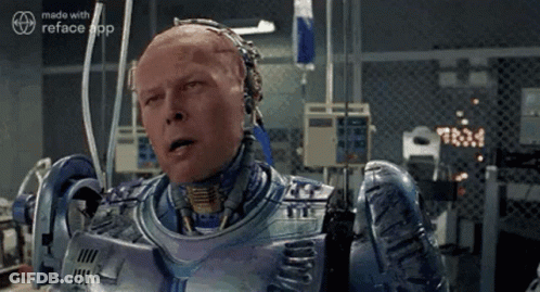 A Man In A Robot Suit Is Sitting In A Room With A Fence . GIF