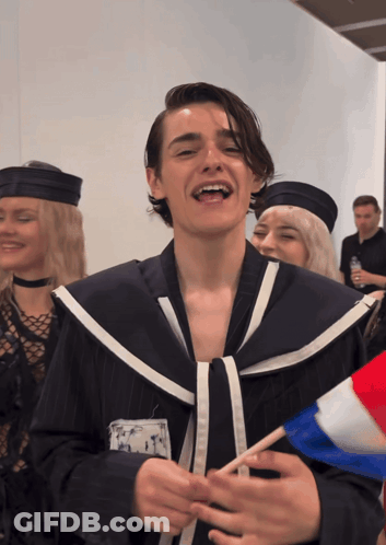 A Man In A Sailor Costume Is Smiling And Holding A French Flag GIF