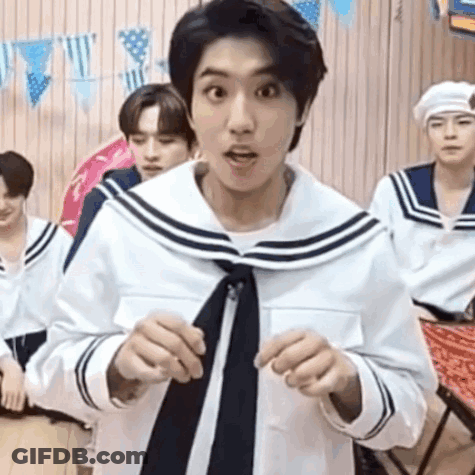 A Man In A Sailor Suit And Tie Is Standing In Front Of A Group Of Young Men . GIF