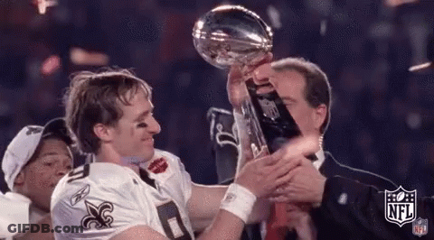A Man In A Saints Jersey Is Holding A Trophy With The NFL Logo On It GIF