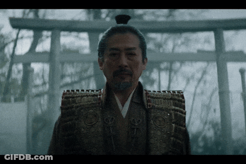 A Man In A Samurai Costume Stands In Front Of A Shrine GIF
