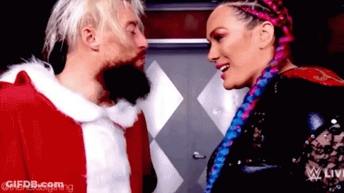 A Man In A Santa Claus Outfit Is Kissing A Woman In A Pink Braid . GIF
