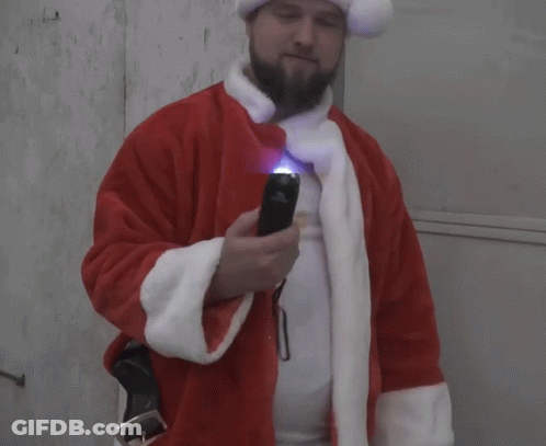 A Man In A Santa Suit Holds A Flashlight GIF