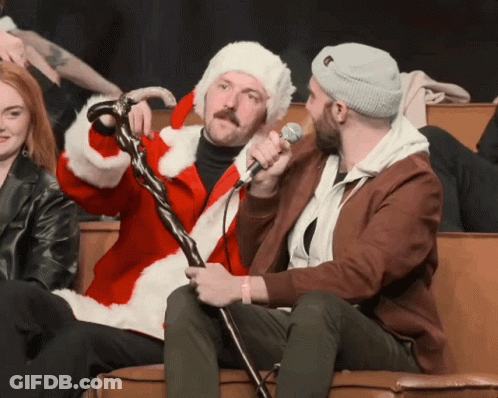 A Man In A Santa Suit Is Holding A Microphone GIF