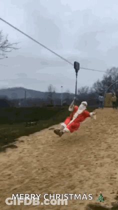 A Man In A Santa Suit Is Riding A Zip Line . GIF